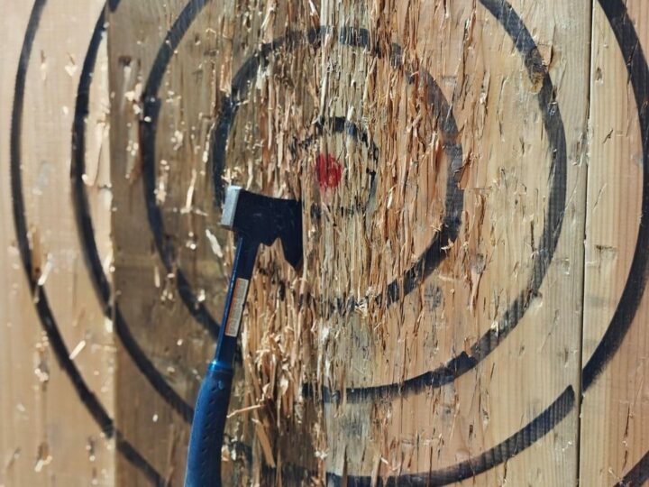 An axe stuck near the bullseye of a wooden target