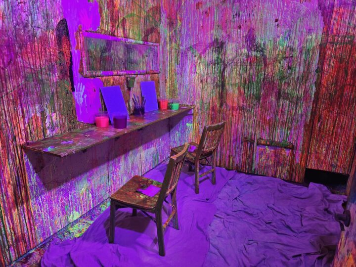 The UV paint splatter room glowing purple, with paint cups on a shelf