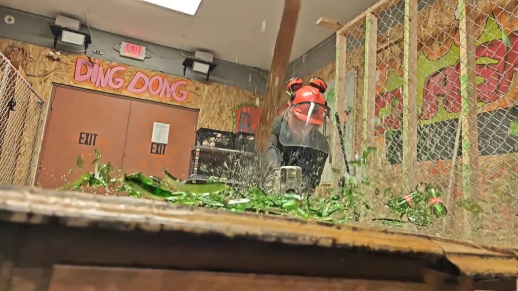 Guest in safety gear smashing breakables in a Ragescape rage room